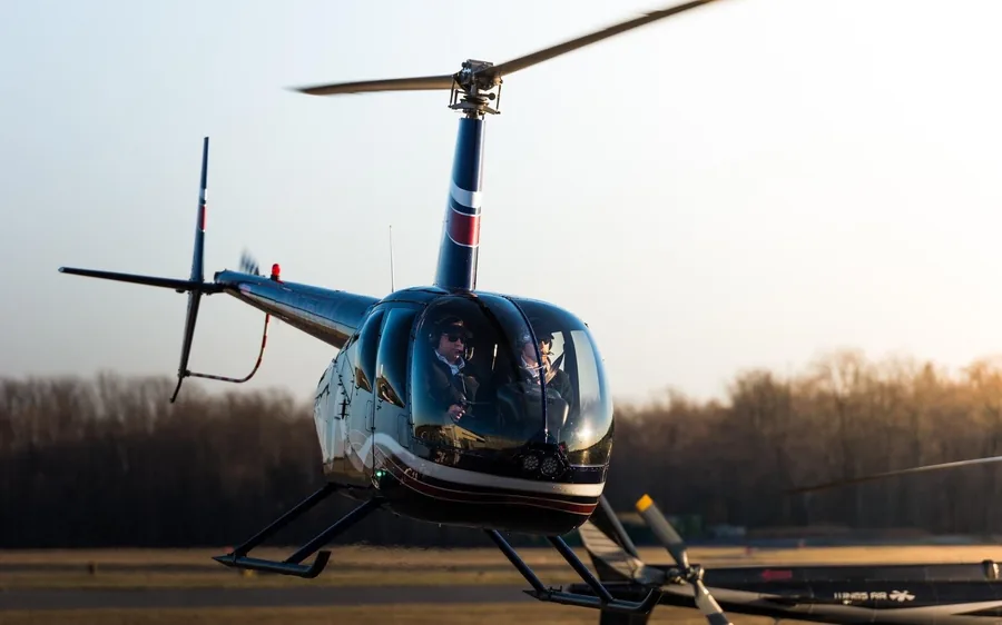 A passenger at the controls of a helicopter with an instructor beside them